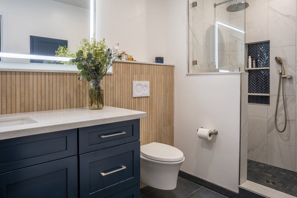 Bathroom remodel with a navy vanity, fluted wall detail, and glass walk-in shower
