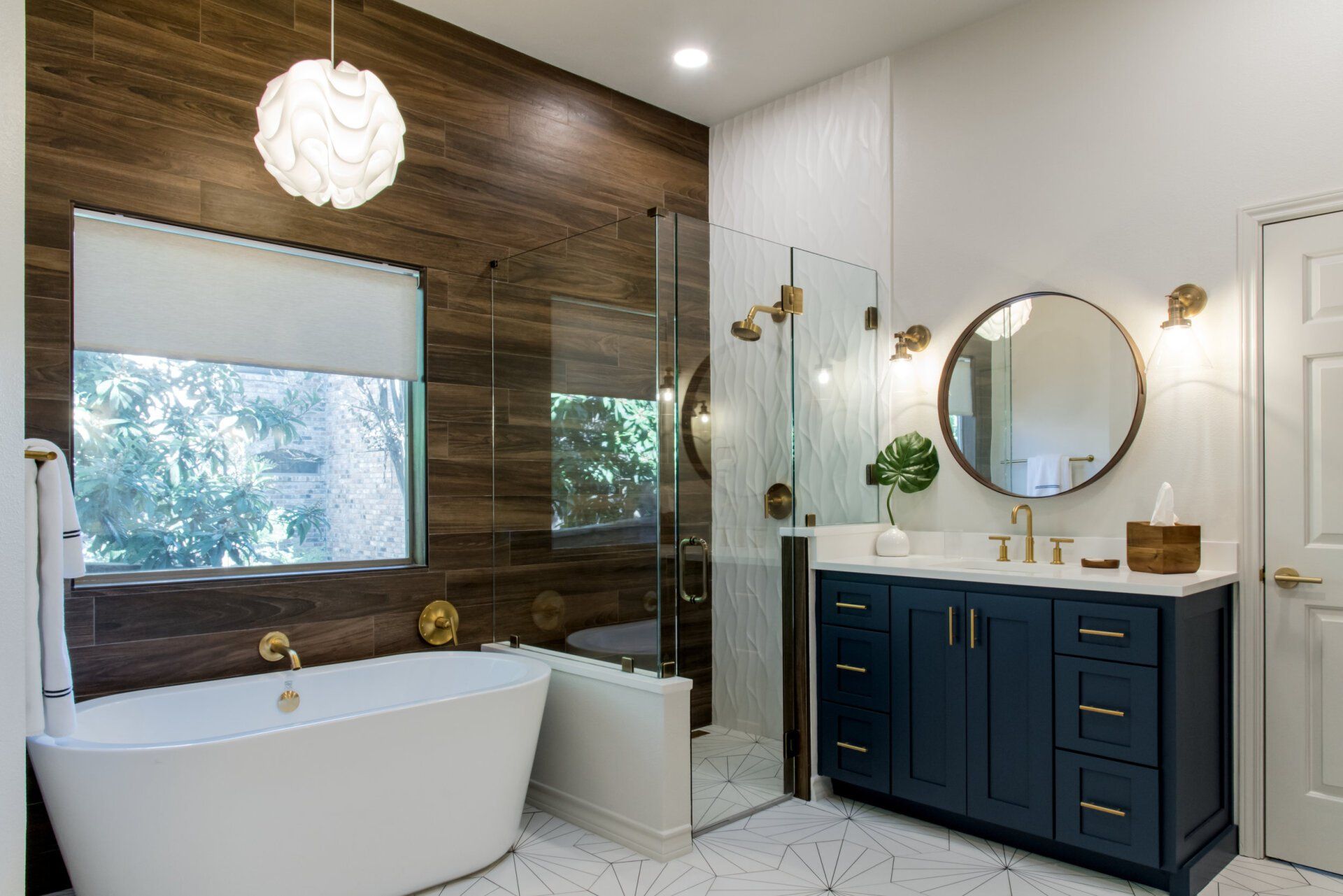 Primary bathroom remodel with navy cabinetry, wood-look shower tile, soaking tub, and brass fixtures